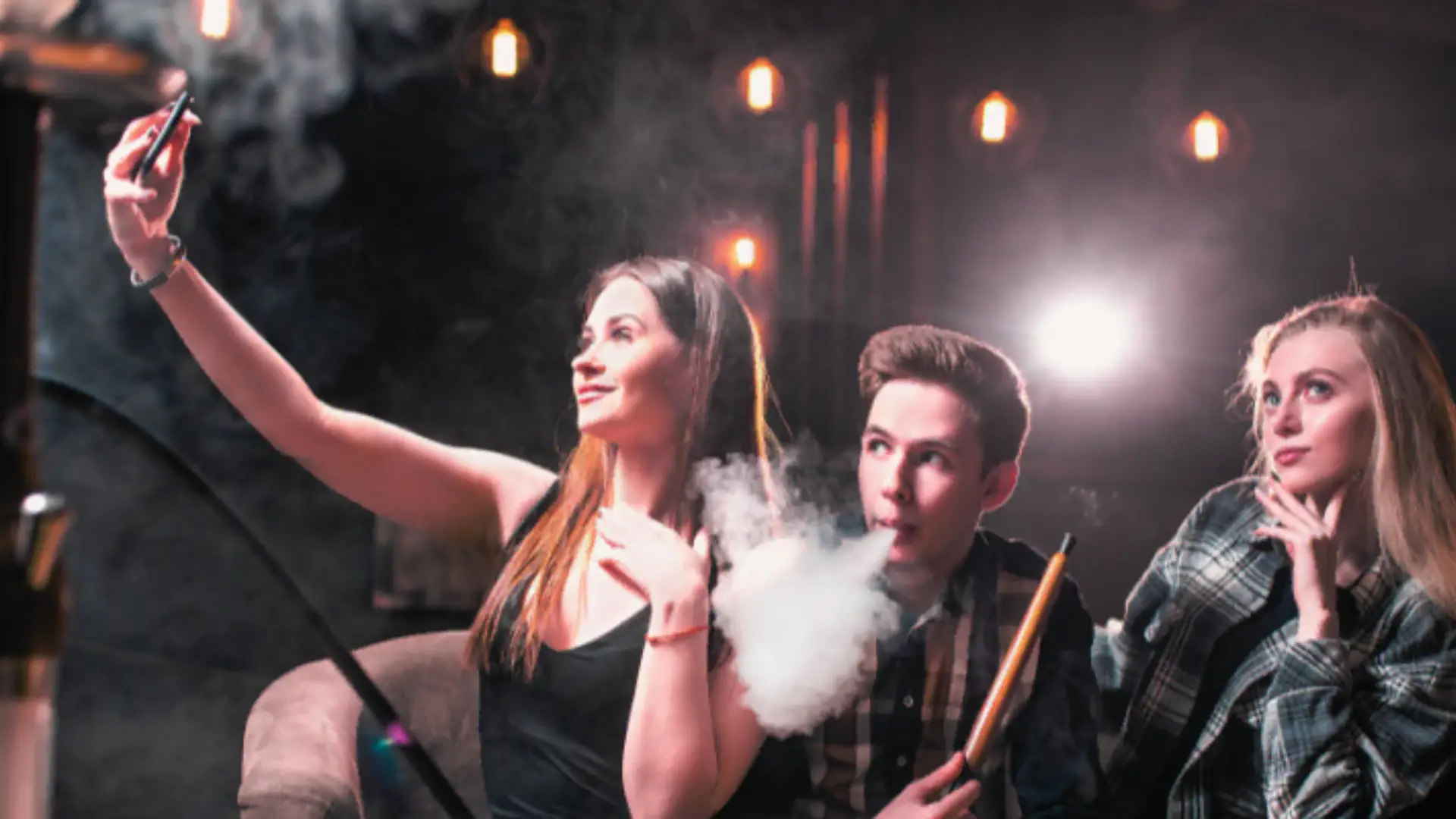 A group of friends enjoying hookah while taking a selfie to post in social media